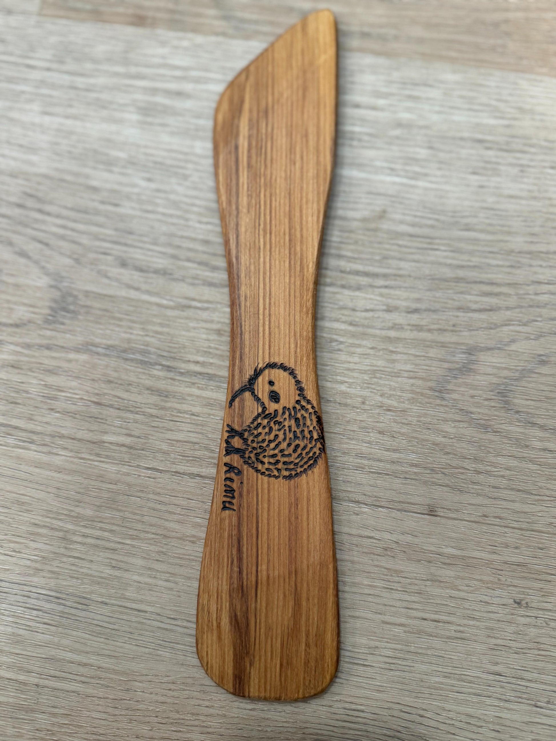 Wooden spoon with a kiwi bird design on a wooden surface