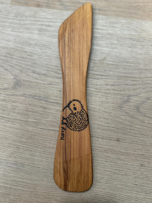 Wooden spoon with a kiwi bird design on a wooden surface