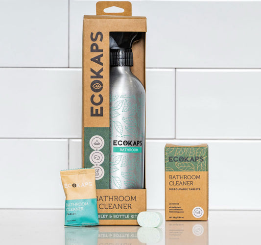 ECOKAPS bathroom cleaning products including a bottle, tablets, and packaging on a tiled bathroom floor.